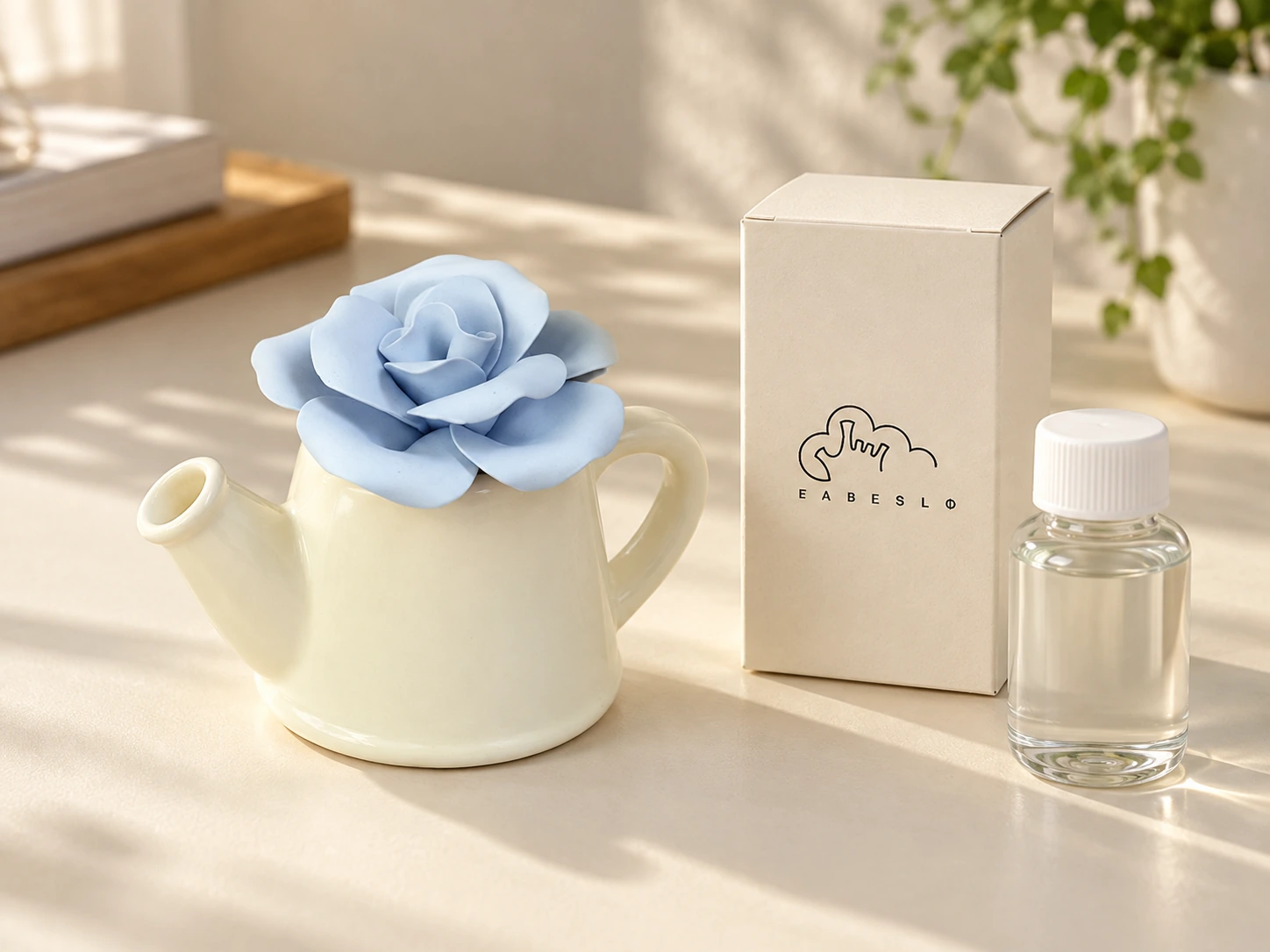 Watering can shaped ceramic diffuser with a handmade blue flower beside a refill bottle and accessory carton.