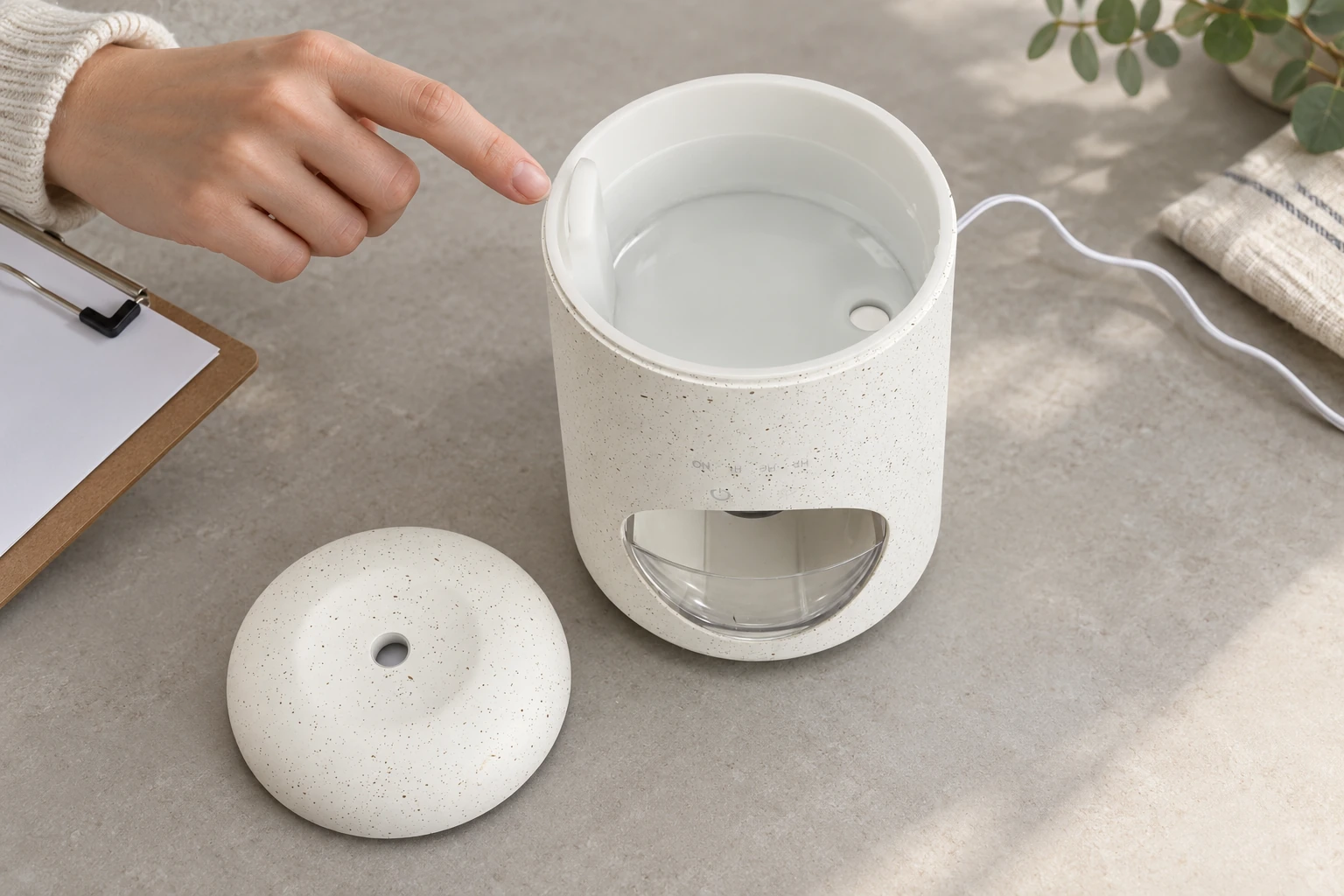 Open white speckled diffuser with its lid beside it and a shallow pool of water remaining in the tank