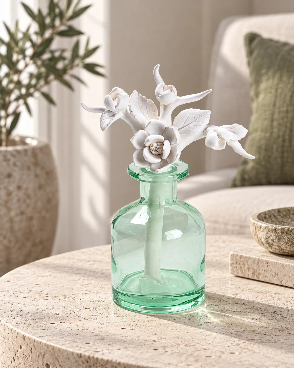 Ceramic floral diffuser with a visible stem inside a green glass vessel.
