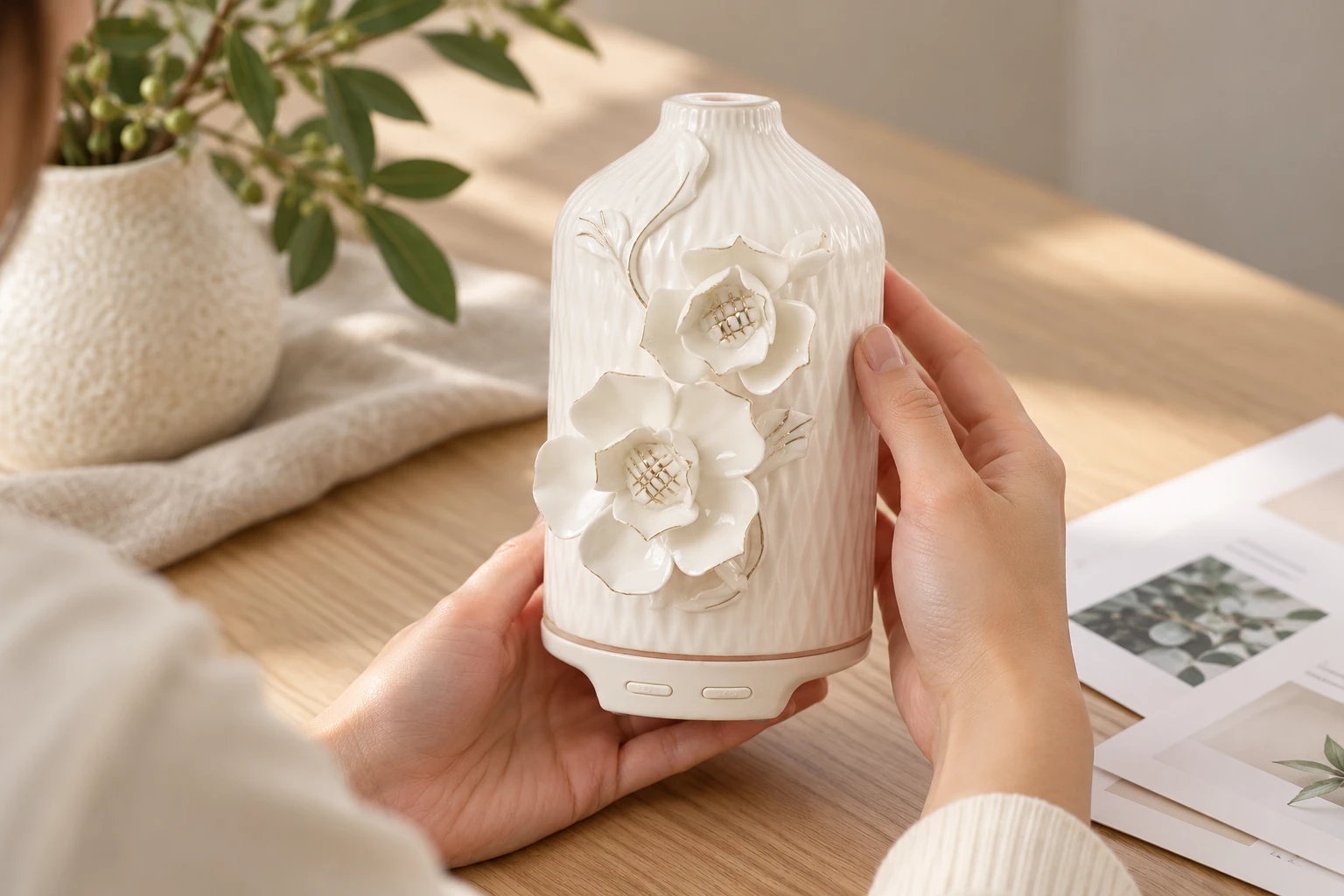 Hands examine a white floral ceramic diffuser beside sample evaluation papers
