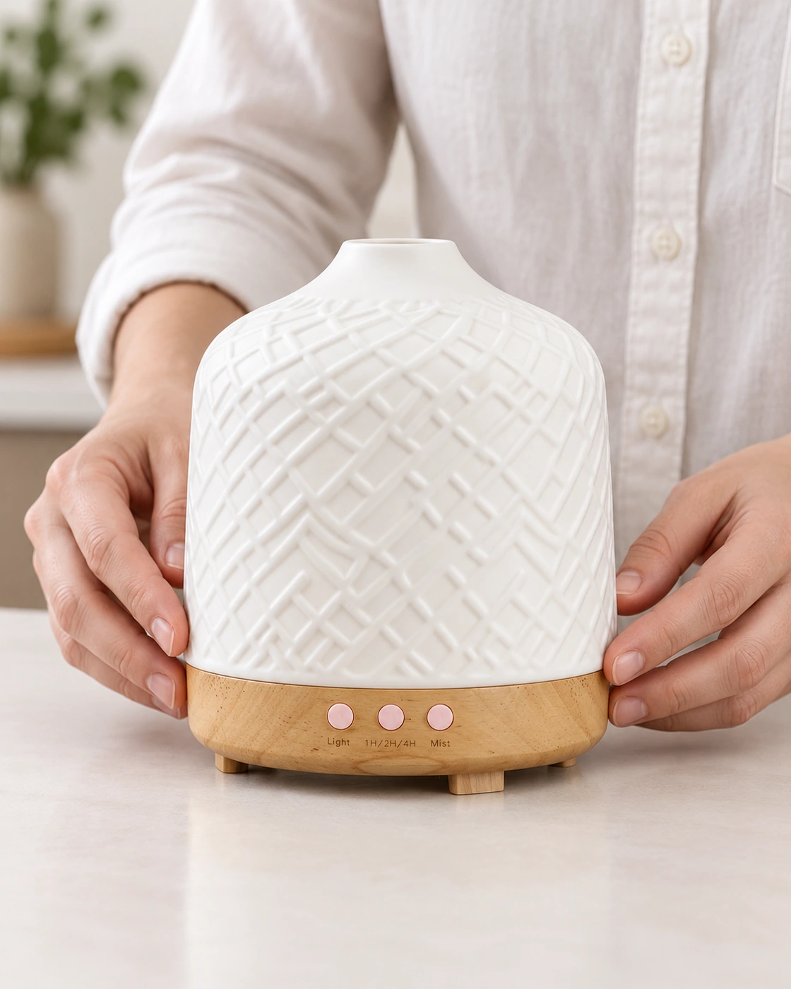 Hands checking the fit between a textured white ceramic diffuser cover and its wooden base.