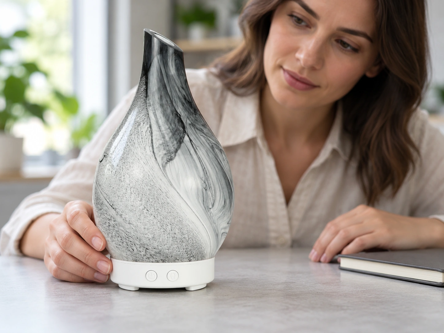 A reviewer examining the grey-white glass cover and assembled base of a decorative ultrasonic diffuser.
