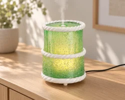 Diffuseur en résine verte translucide en forme de gâteau d'anniversaire, orné d'une bordure torsadée blanche, posé sur une console de salon